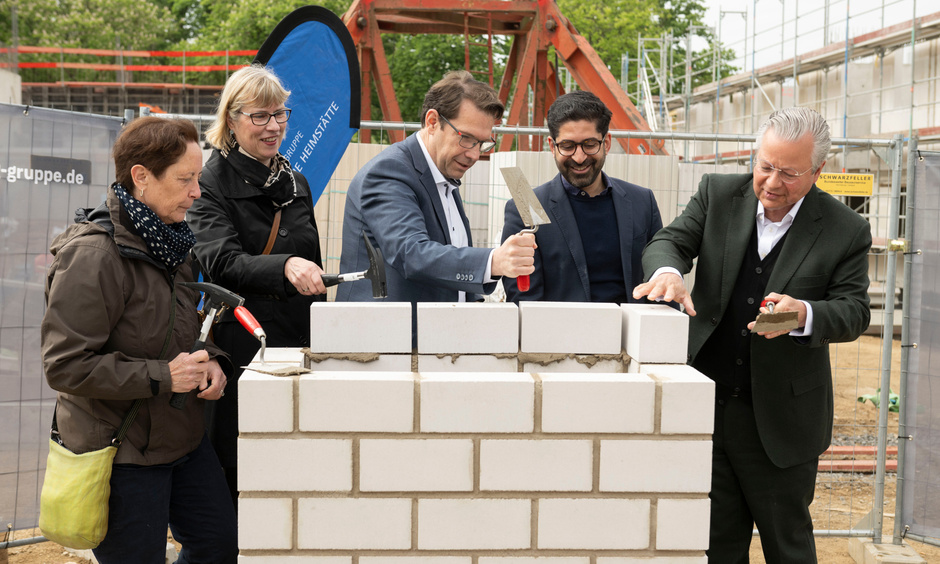 Die genannten Personen mauern die Zeitkapsel ein.