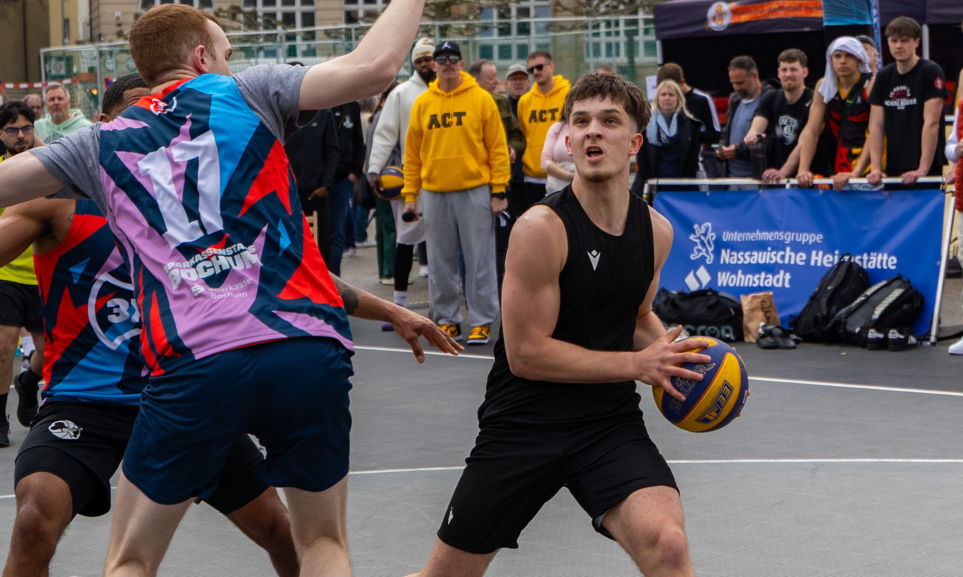 Zwei junge Männer im Zweikampf mit dem Ball unter dem Basketballkorb.