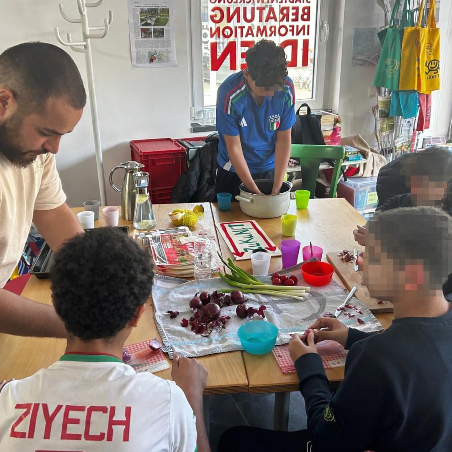 Das Bild zeigt die "Mein Stern" Gruppe bei der gemeinsamen Koch-Arbeit. Zu sehen sind Kinder sowie Gruppenleiter Walid Aitoutalamte