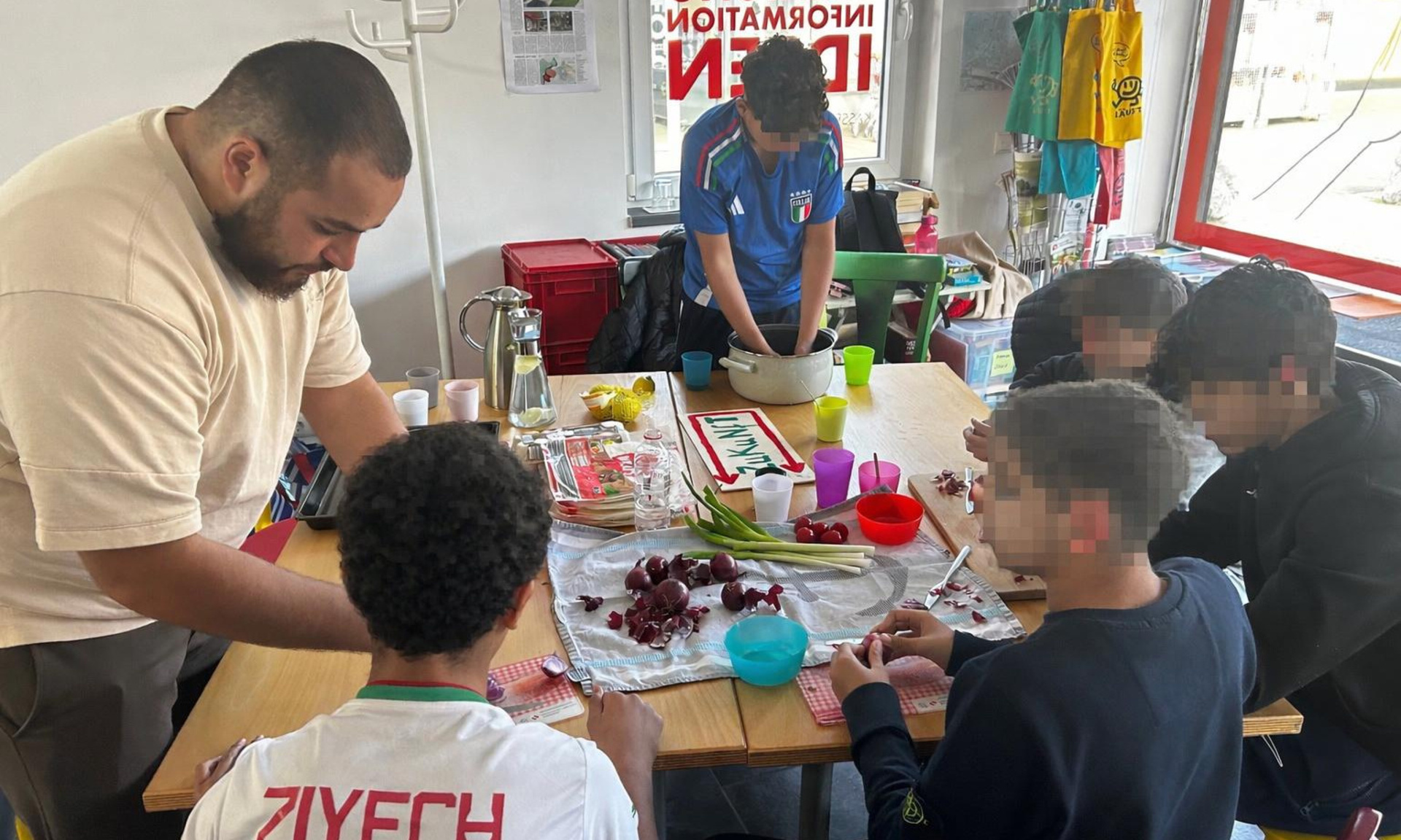 Das Bild zeigt die "Mein Stern" Gruppe bei der gemeinsamen Koch-Arbeit. Zu sehen sind Kinder sowie Gruppenleiter Walid Aitoutalamte