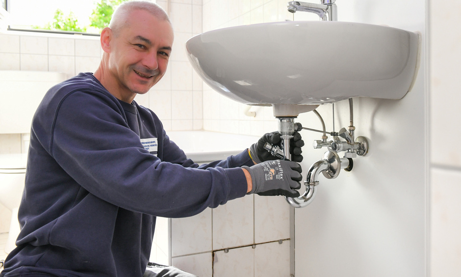 Handwerker repariert das Abflussrohr am Waschbecken.