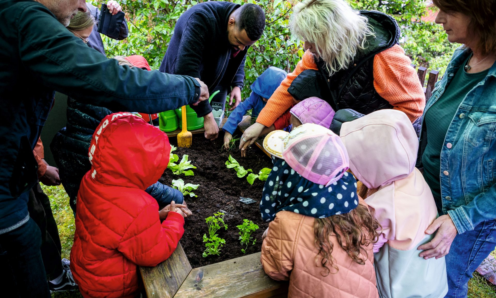 Kinder und Erwachsene bepflanzen gemeinsam ein Hochbeet