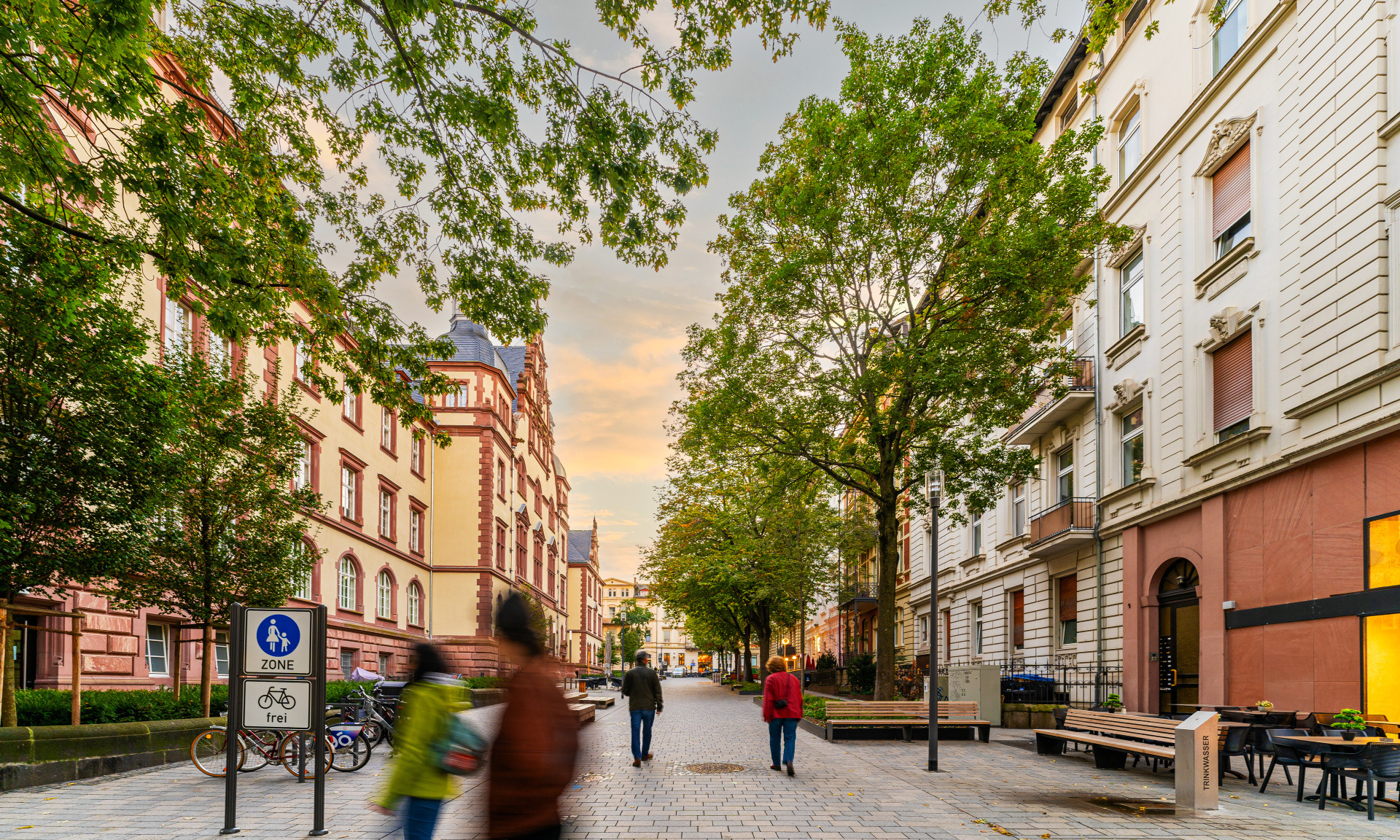 Fußgängerzone mit Bäumen und Passanten, links das Alte Gericht in Wiesbaden.