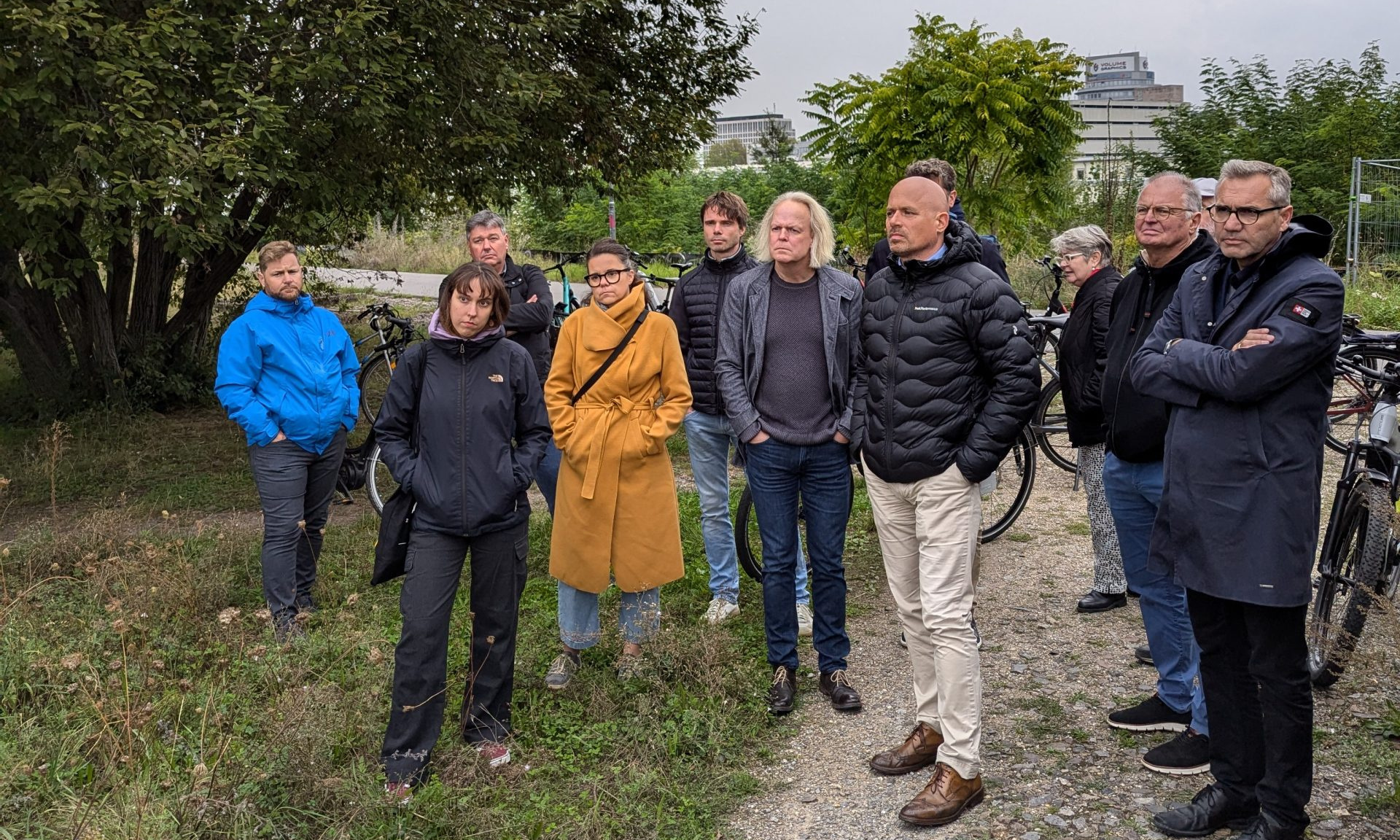 Mehrere Menschen stehen im Freien und hören anderen Menschen zu, die aber nicht zu sehen sind