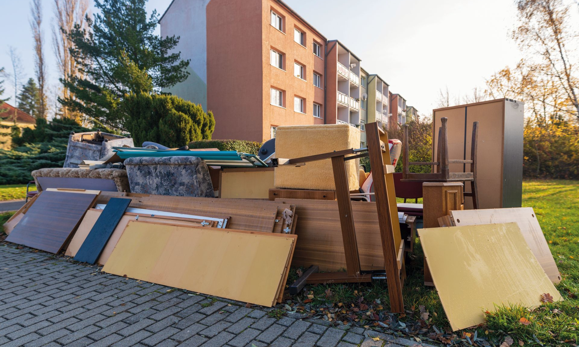 Sperrmüllablagerung im Vordergrund. Im Hintergrund ist ein Hochhaus