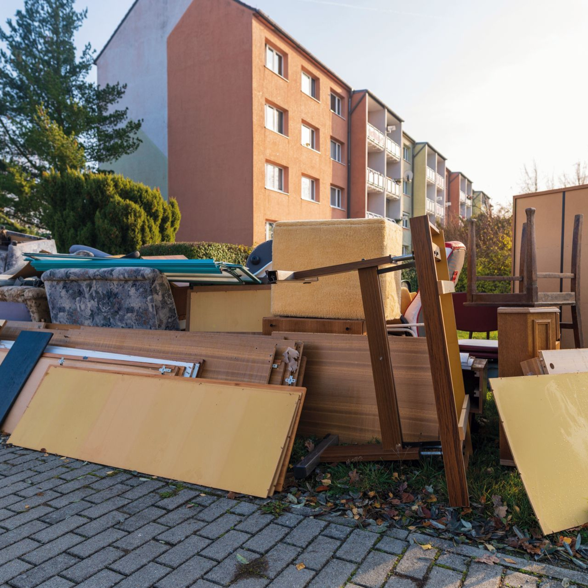 Sperrmüllablagerung im Vordergrund. Im Hintergrund ist ein Hochhaus