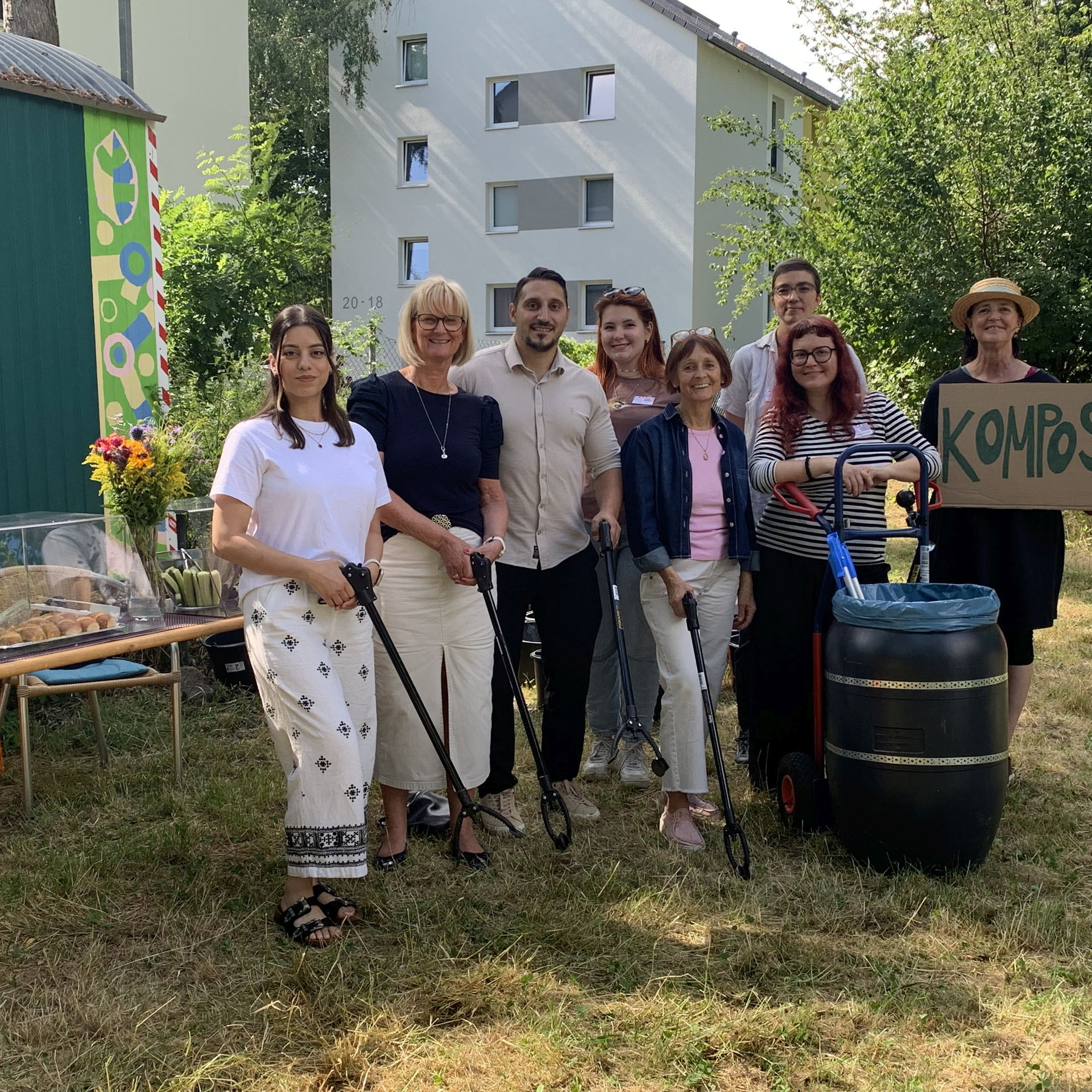 Gruppe von 6 Personen die zusammensteht und in die Kamera schauen. Eine Person hält ein Schild mit "Kostbar" hoch