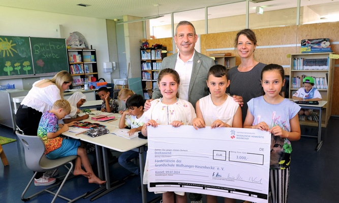 NHW-Regionalcenterleiter Sascha Holstein und Jennifer Linke von der Sozialen Quartiersentwicklung der NHW überreichen den Spendenscheck an drei Kinder.