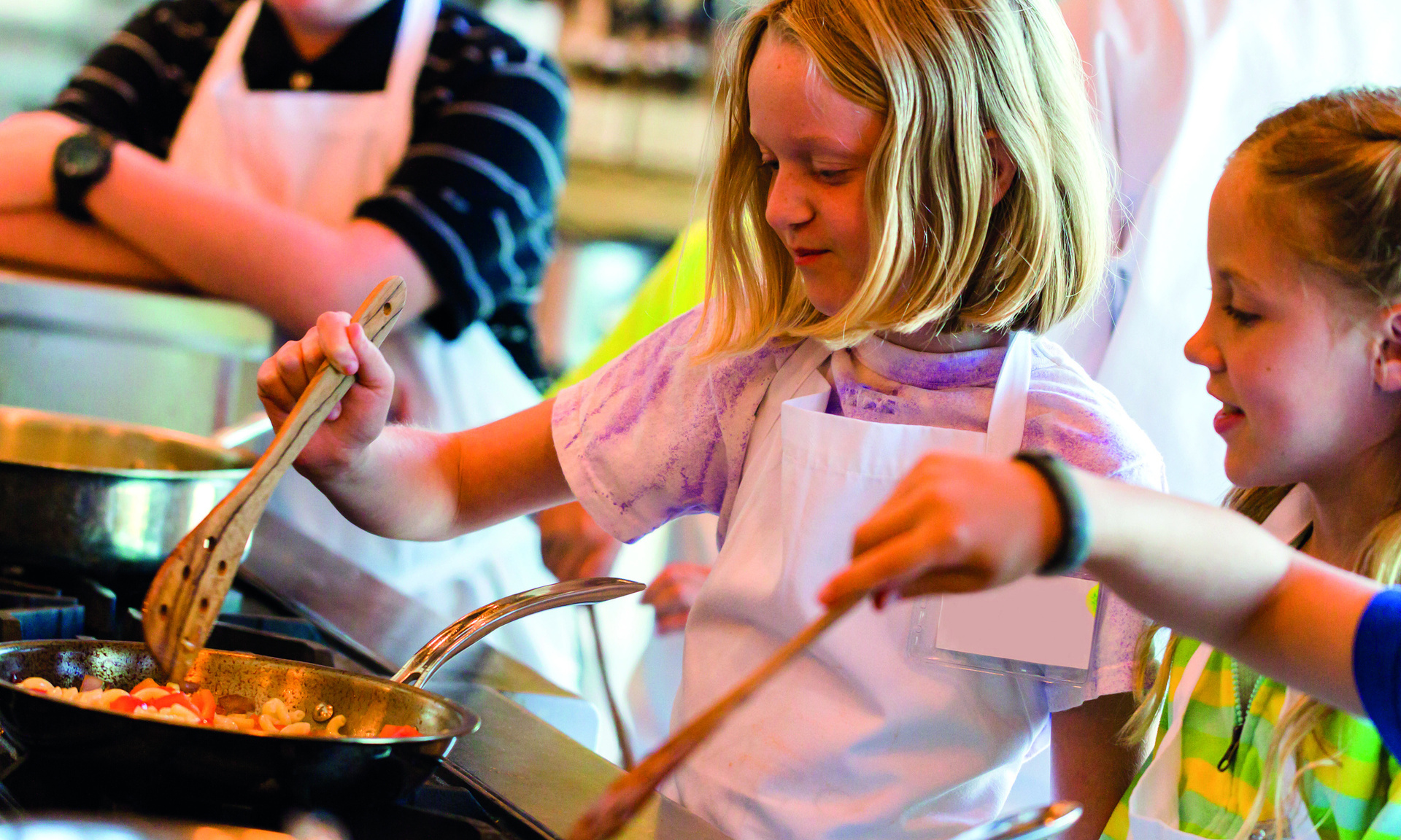 Kleinere Kinder stehen am Herd und kochen