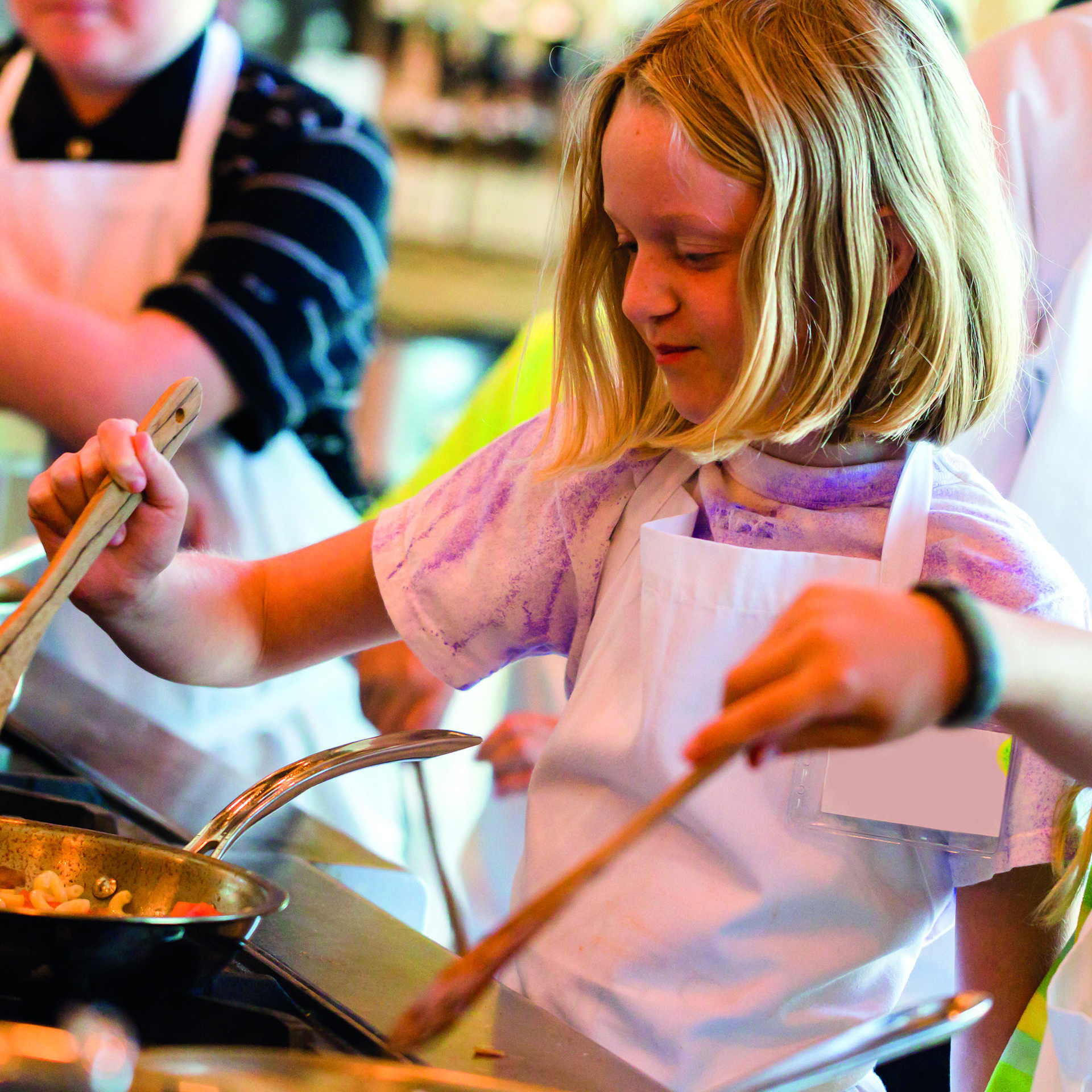 Kleinere Kinder stehen am Herd und kochen