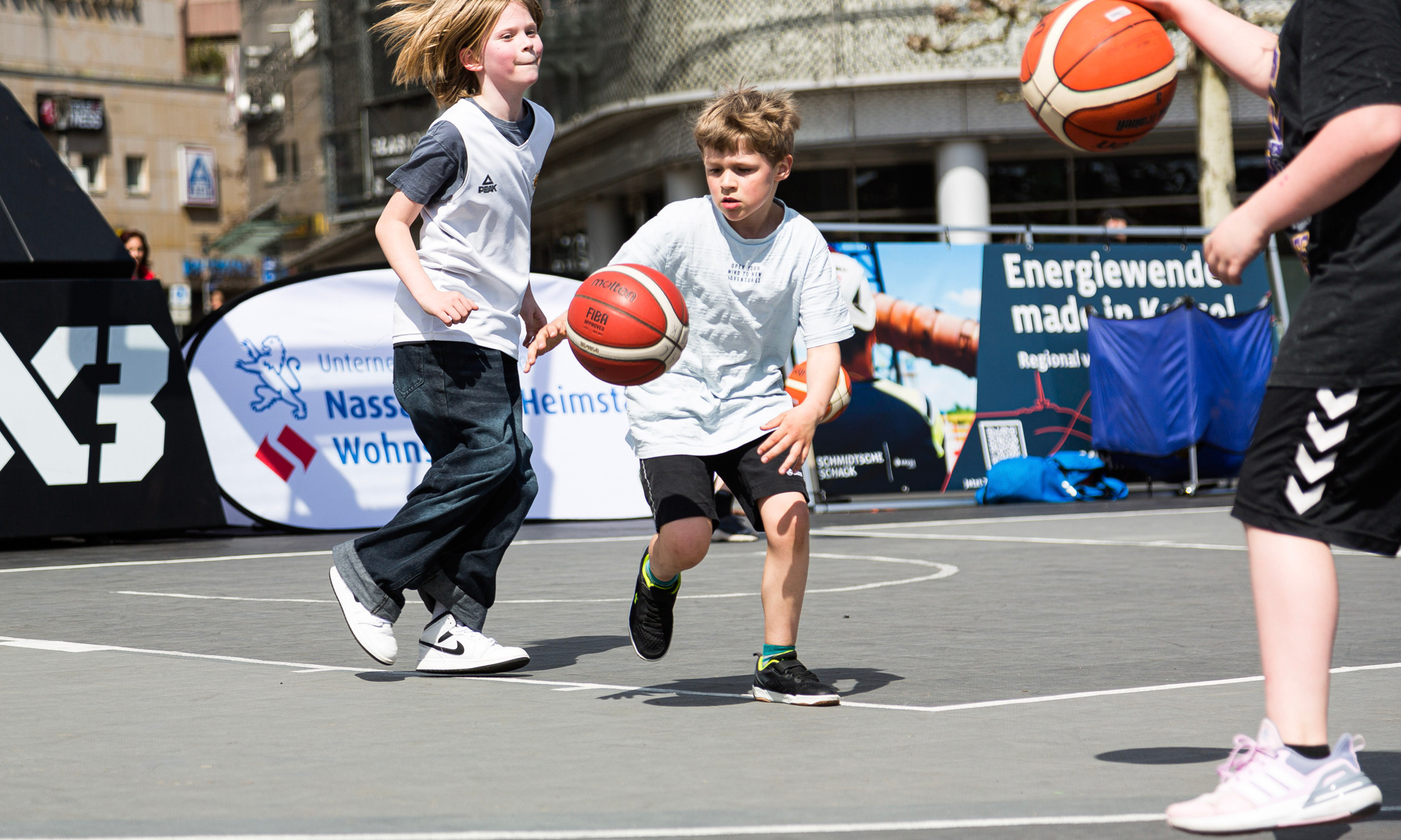 Mehrere Kinder spielen auf einem Street Court Basketball