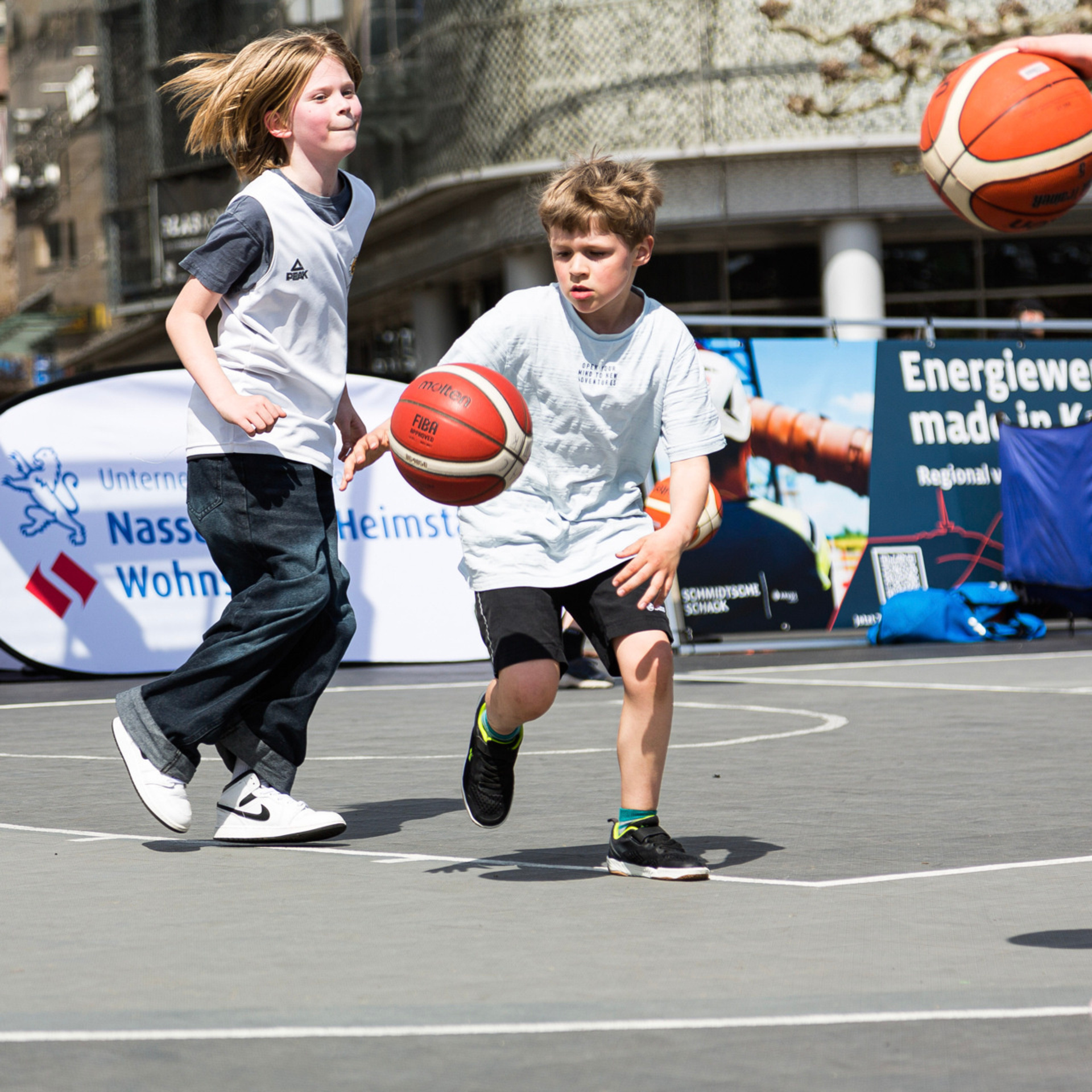 Mehrere Kinder spielen auf einem Street Court Basketball