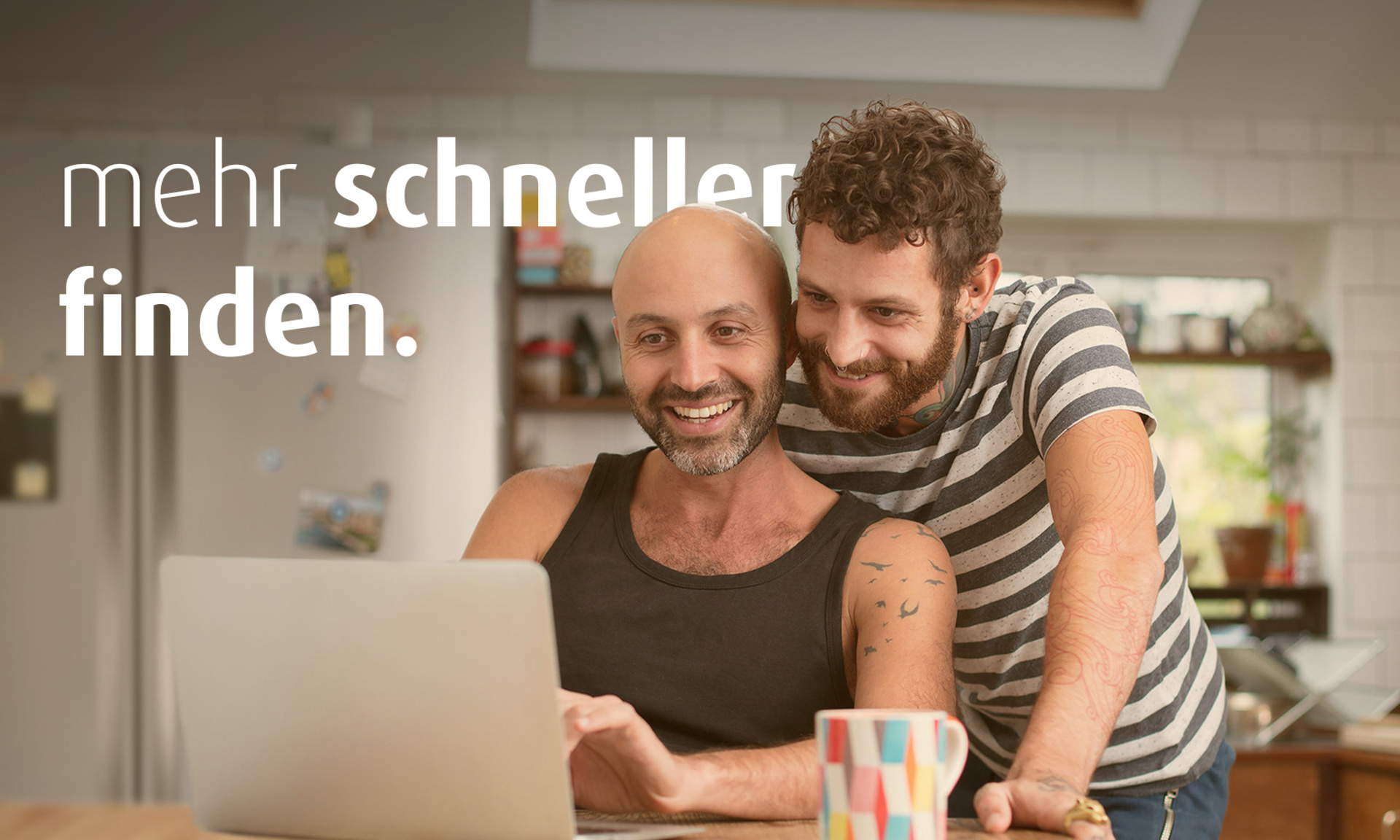 Zwei Männer sind in der Küche und schauen gemeinsam auf einen Laptop. Auf dem Bild steht "mehr schneller finden".
