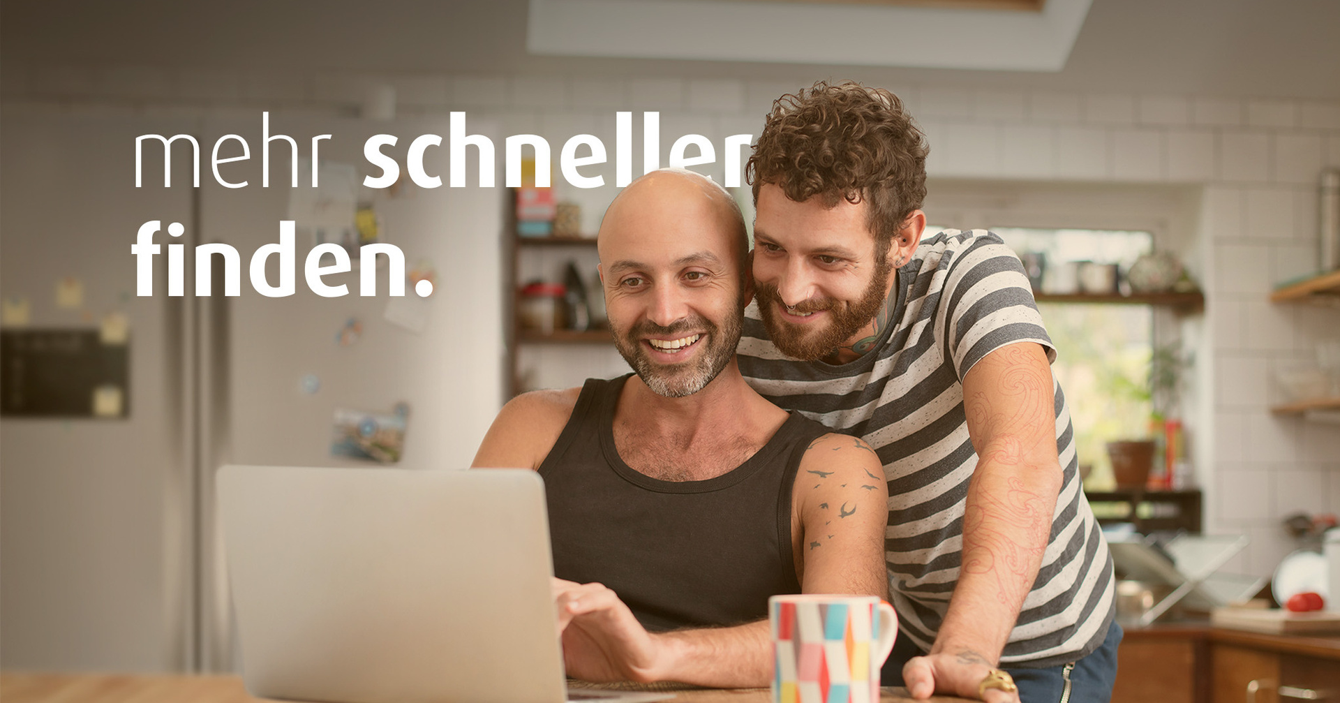 Zwei Männer sind in der Küche und schauen gemeinsam auf einen Laptop. Auf dem Bild steht "mehr schneller finden".