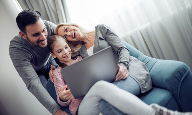 Eine Familie (eine Frau, ein Mann, ein Kind), schauen gemeinsam auf einen Laptop-Bildschirm