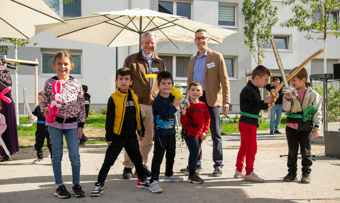 Zwei Erwachsene und viele Kinder mit Luftballonfiguren, alle lachen