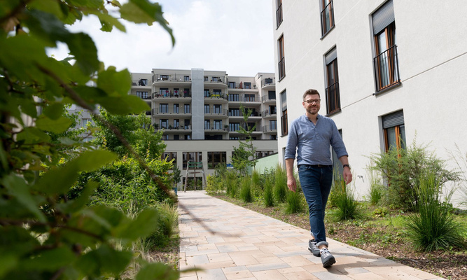Mann geht durch Wohnquartier, im Vordergrund ist Grün