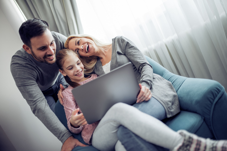 Mann, Frau und Mädchen sitzen auf dem Sofa mit einem Laptop.