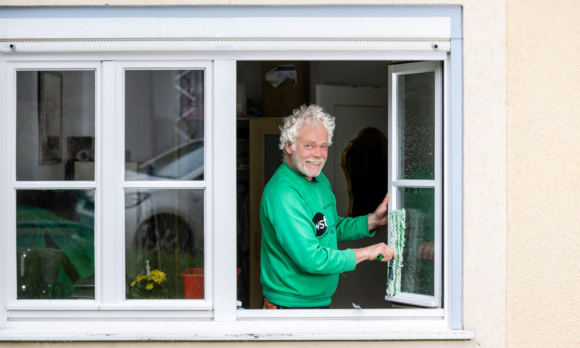 Ein WST-Mitarbeiter putzt ein Fenster.