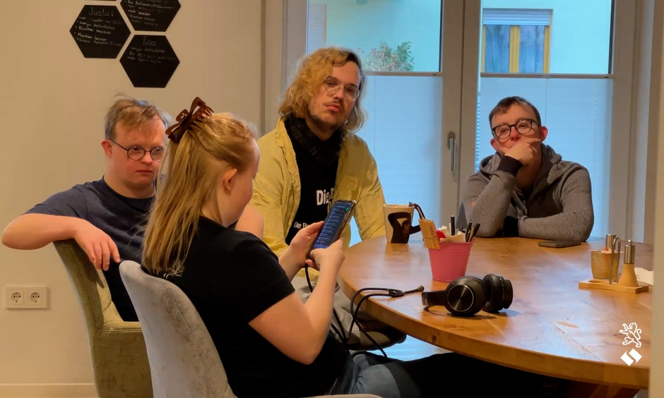 Die Bewohner sitzen um einen Tisch in ihrer Wohnung.