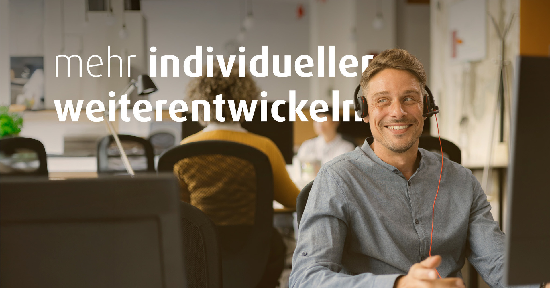 Ein Mann sitzt am Schreibtisch und hat ein Headset auf. Im Hintergrund sieht man weitere Personen an Schreibtischen. Auf dem Bild steht der Text "mehr individueller weiterentwickeln".