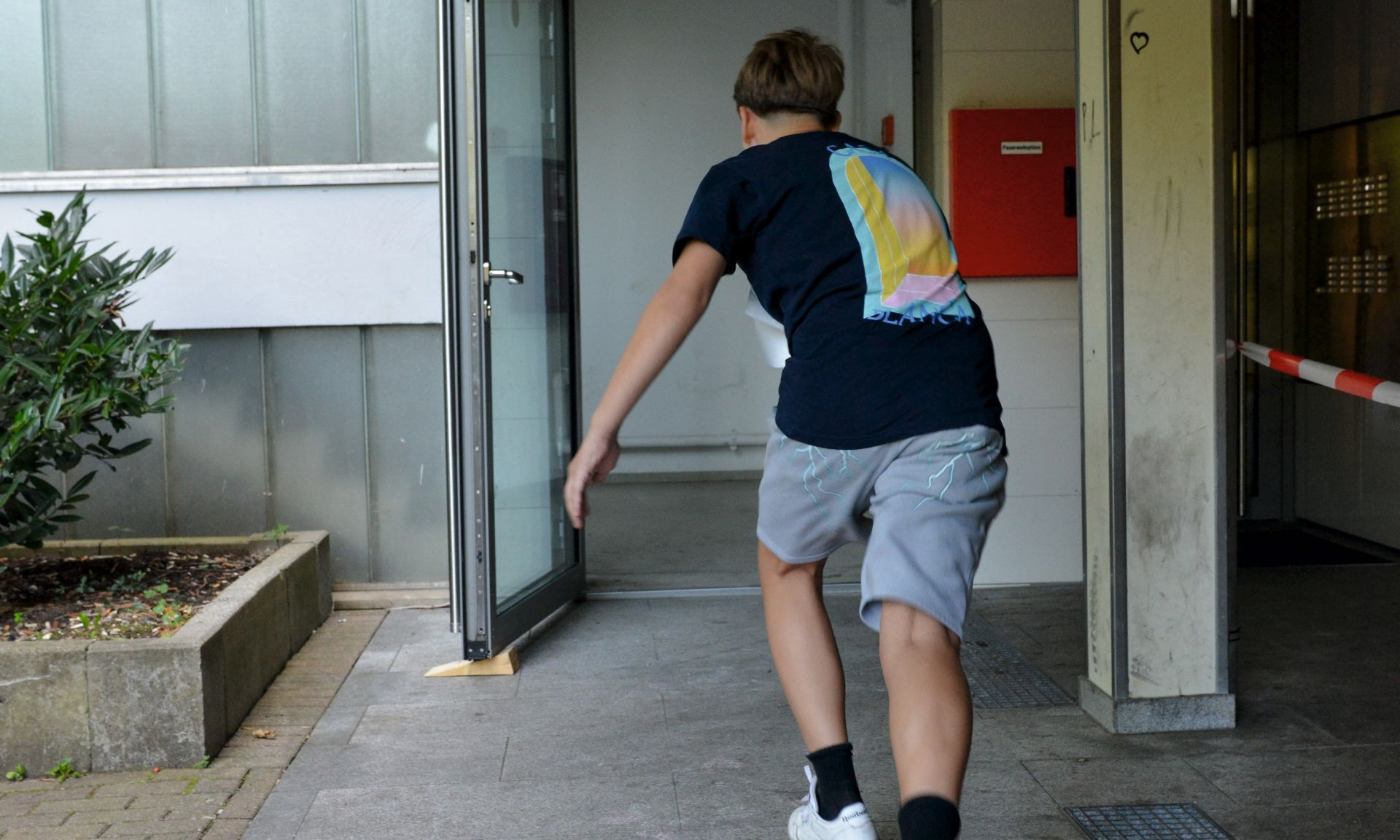 Auf dem Boden steht "Start" ein Junge rennt grade los in einen Hauseingang.