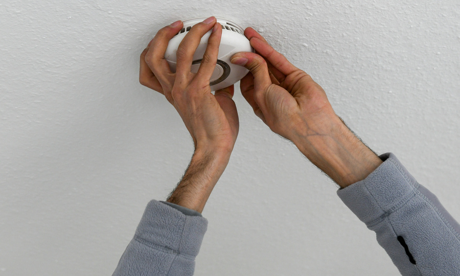 Handwerker montiert einen Rauchwarnmelder an der Decke.