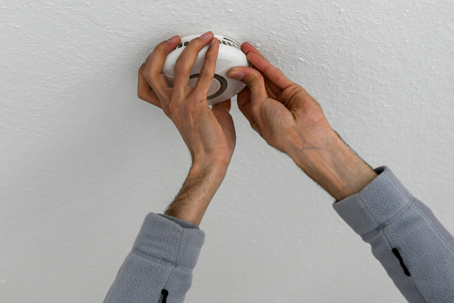 Handwerker montiert einen Rauchwarnmelder an der Decke.