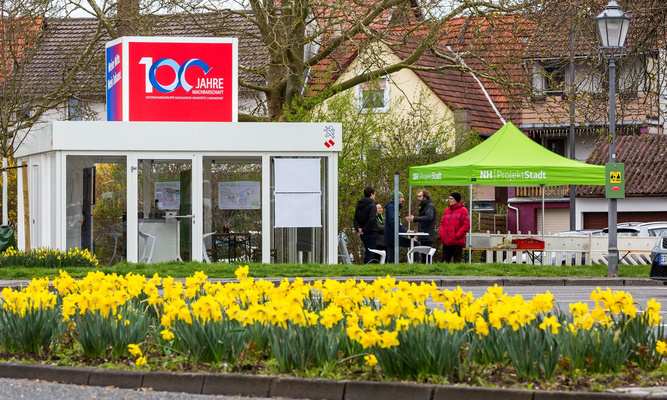 Der Info-Cube der NHW mit 100-Jahre-Logo und ein Stand der ProjektStadt