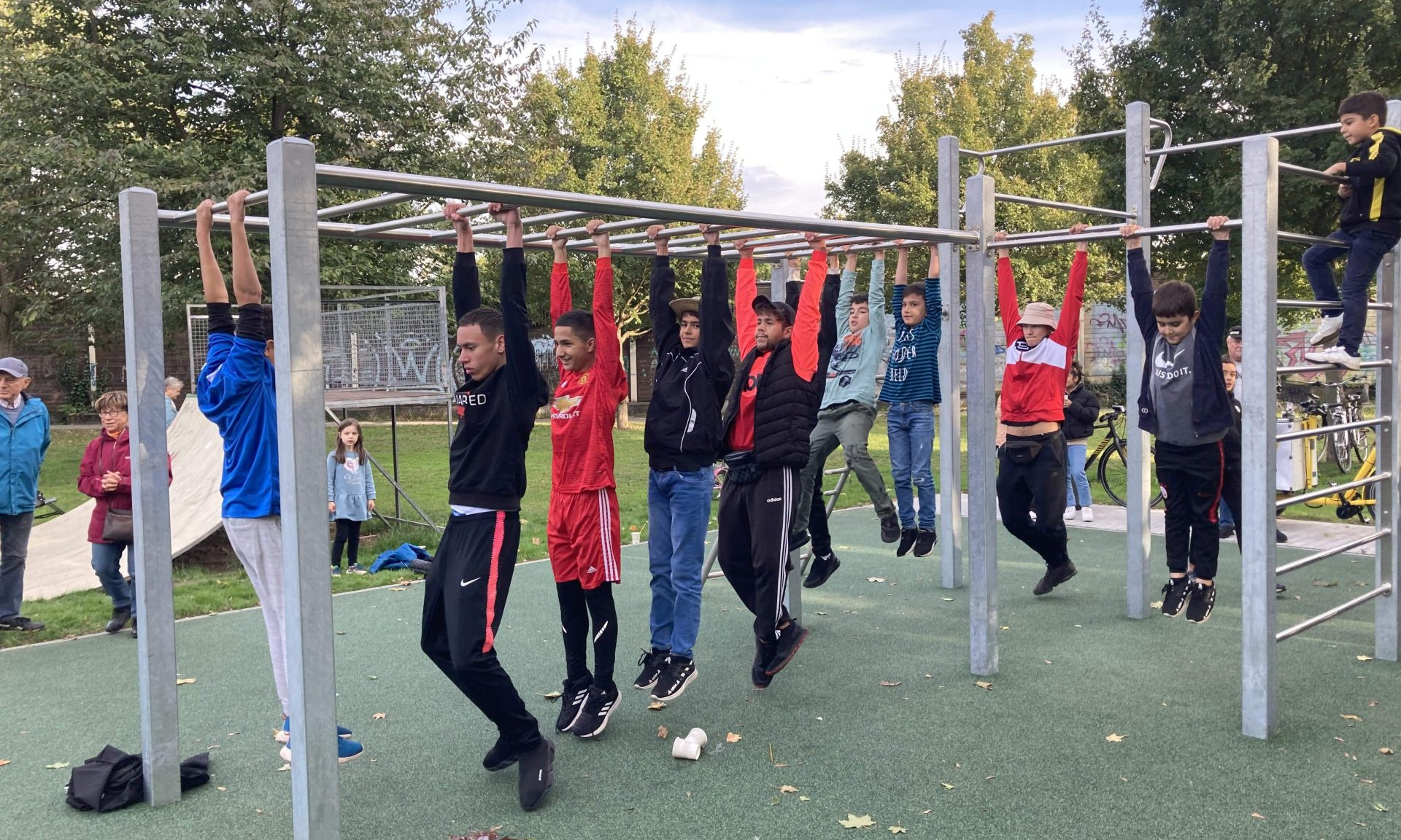 Mehrere junge Menschen hangeln sich an einem Fitnessgerät entlang