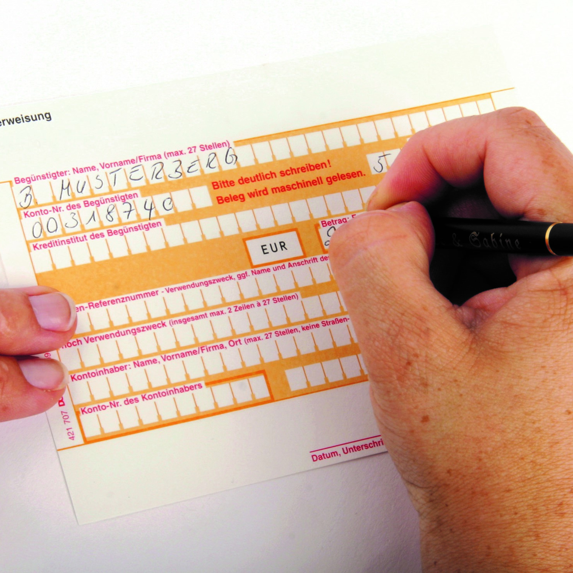 Stockfoto von einem Überweisungsträger und einer Hand, die das Formular ausfüllt