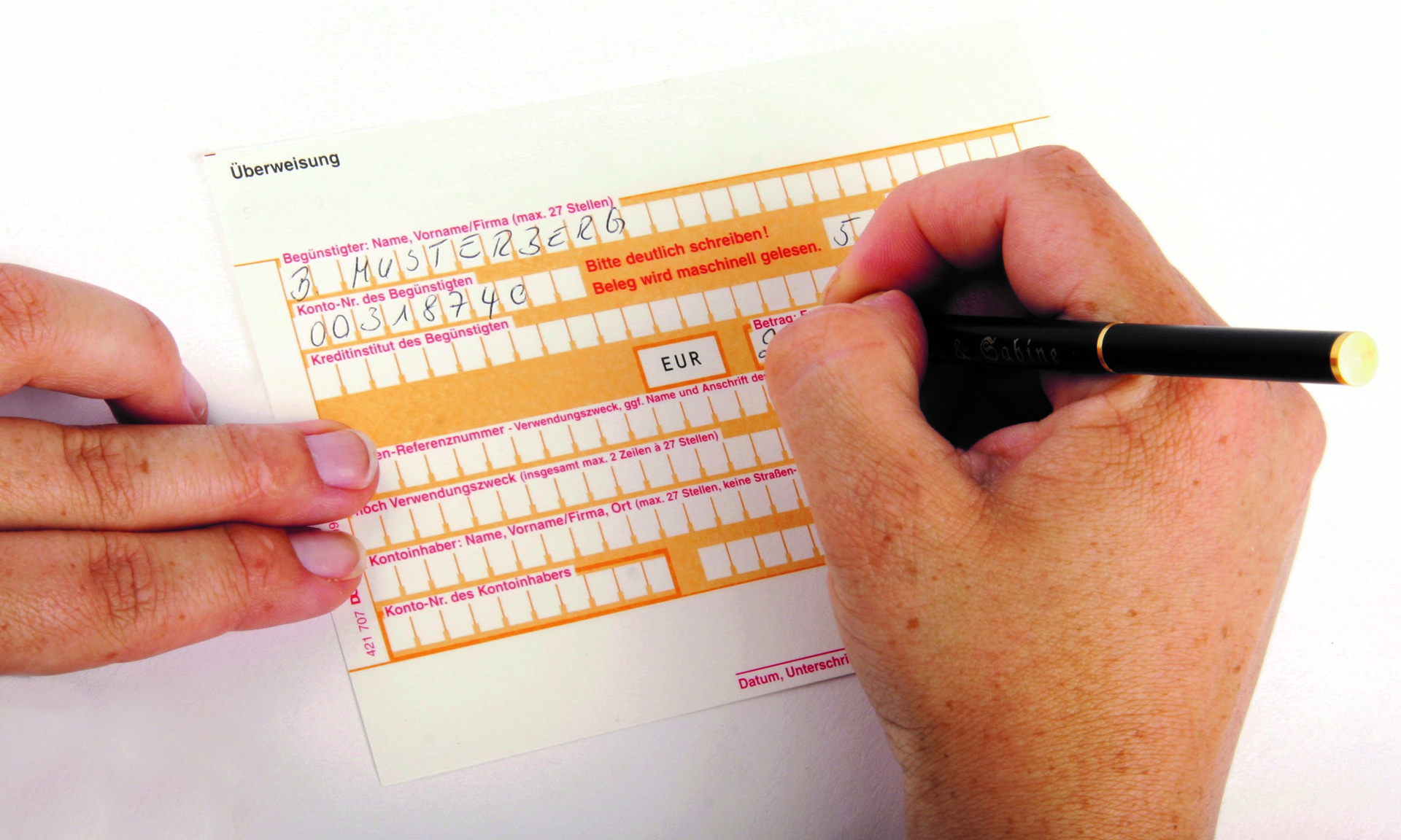 Stockfoto von einem Überweisungsträger und einer Hand, die das Formular ausfüllt
