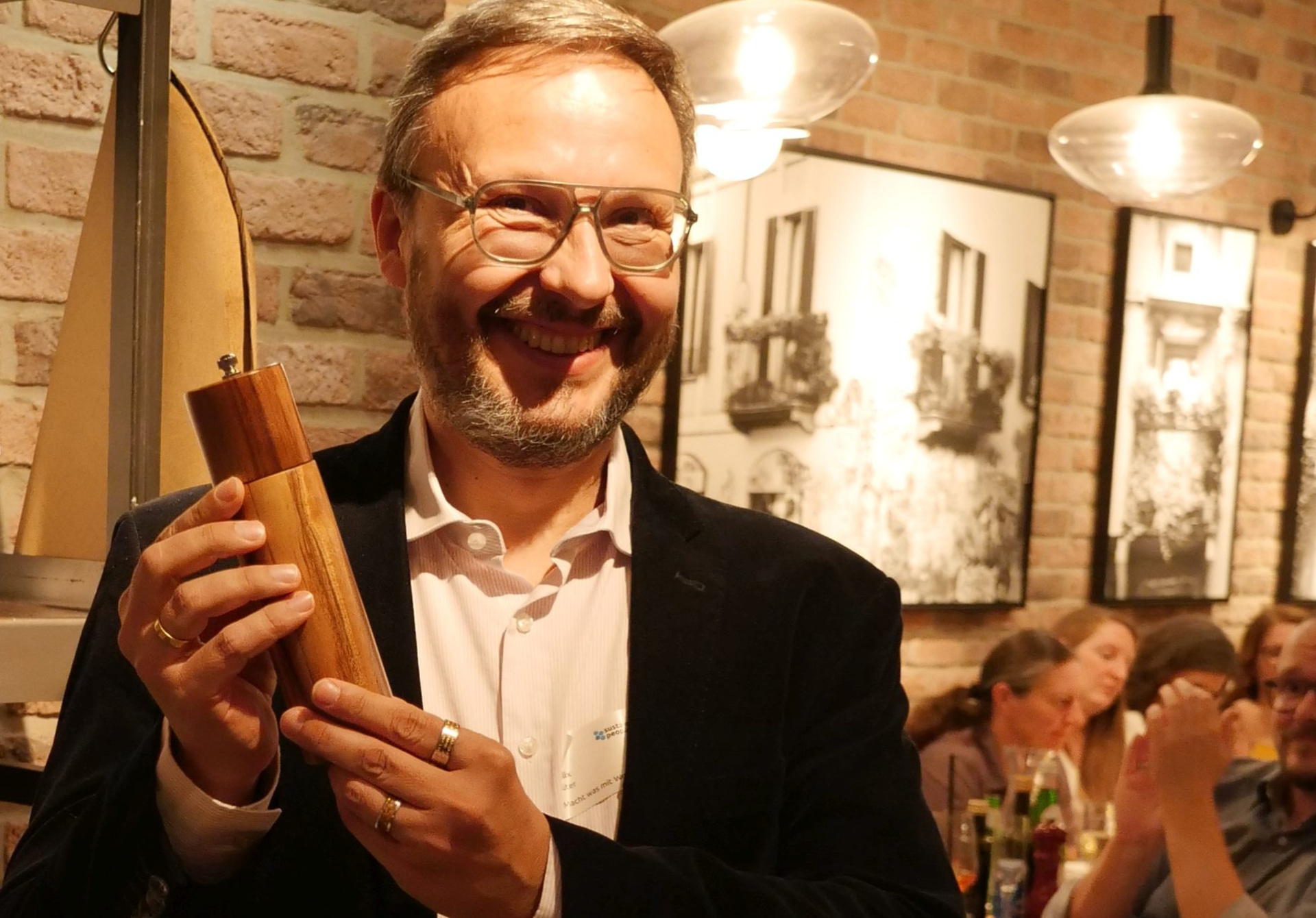 Felix Lüter bei der Preisverleihung in Frankfurt am Main. Er strahlt und hält etwas in der Hand, das aussieht wie ein Salzstreuer oder eine Pfeffermühle.