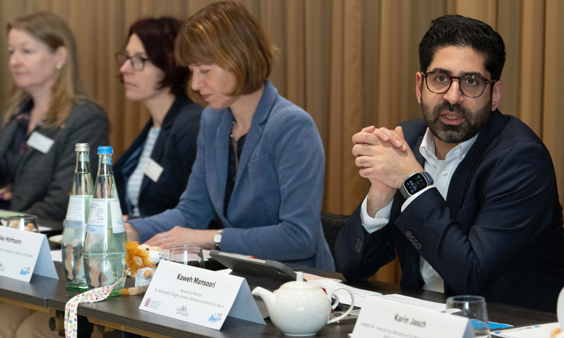 Wirtschaftsminister Kaweh Mansoori und Sozialministerin Heike Hofmann sitzen nebeneinander an einem Tisch, davor Namensschilder und Wasserflaschen