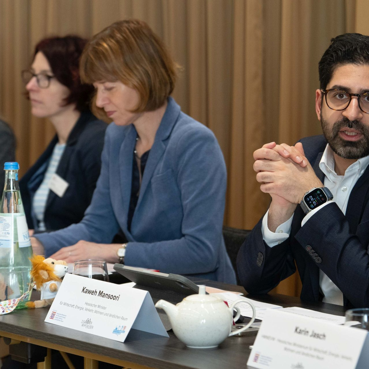 Wirtschaftsminister Kaweh Mansoori und Sozialministerin Heike Hofmann sitzen nebeneinander an einem Tisch, davor Namensschilder und Wasserflaschen