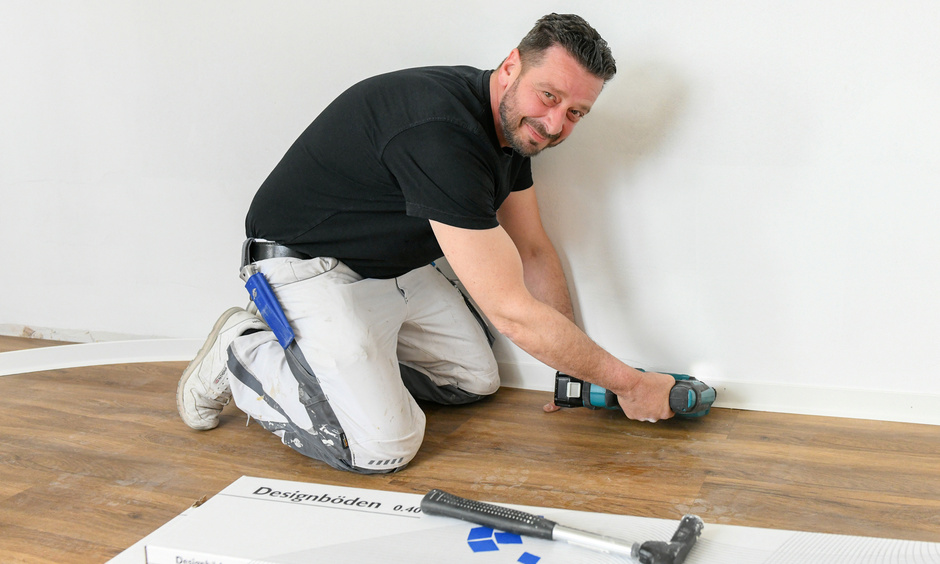 Handwerker montiert eine Fußbodenleiste.