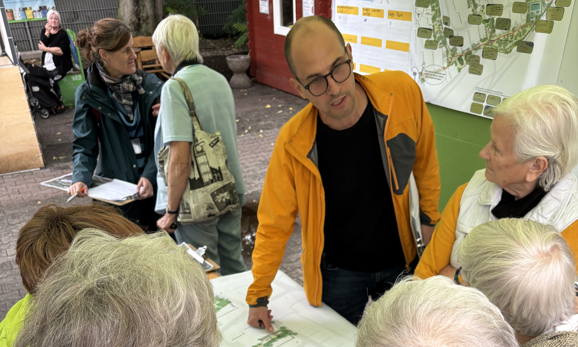 Ältere Menschen stehen um einen Planungstisch herum und schauen gespannt auf den dort präsentierten Plan.