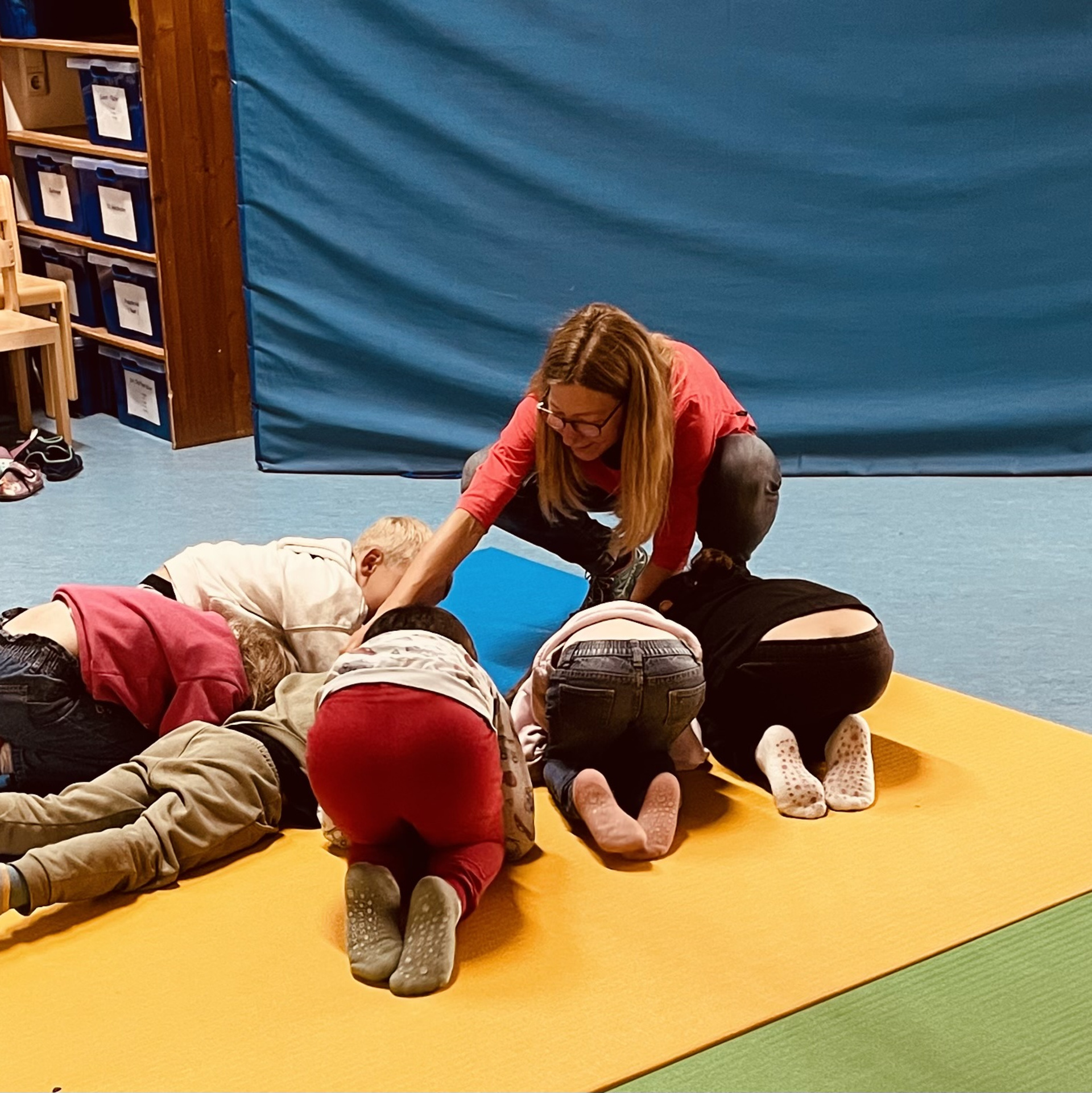 Kinder auf einer Turnmatte die Übungen machen