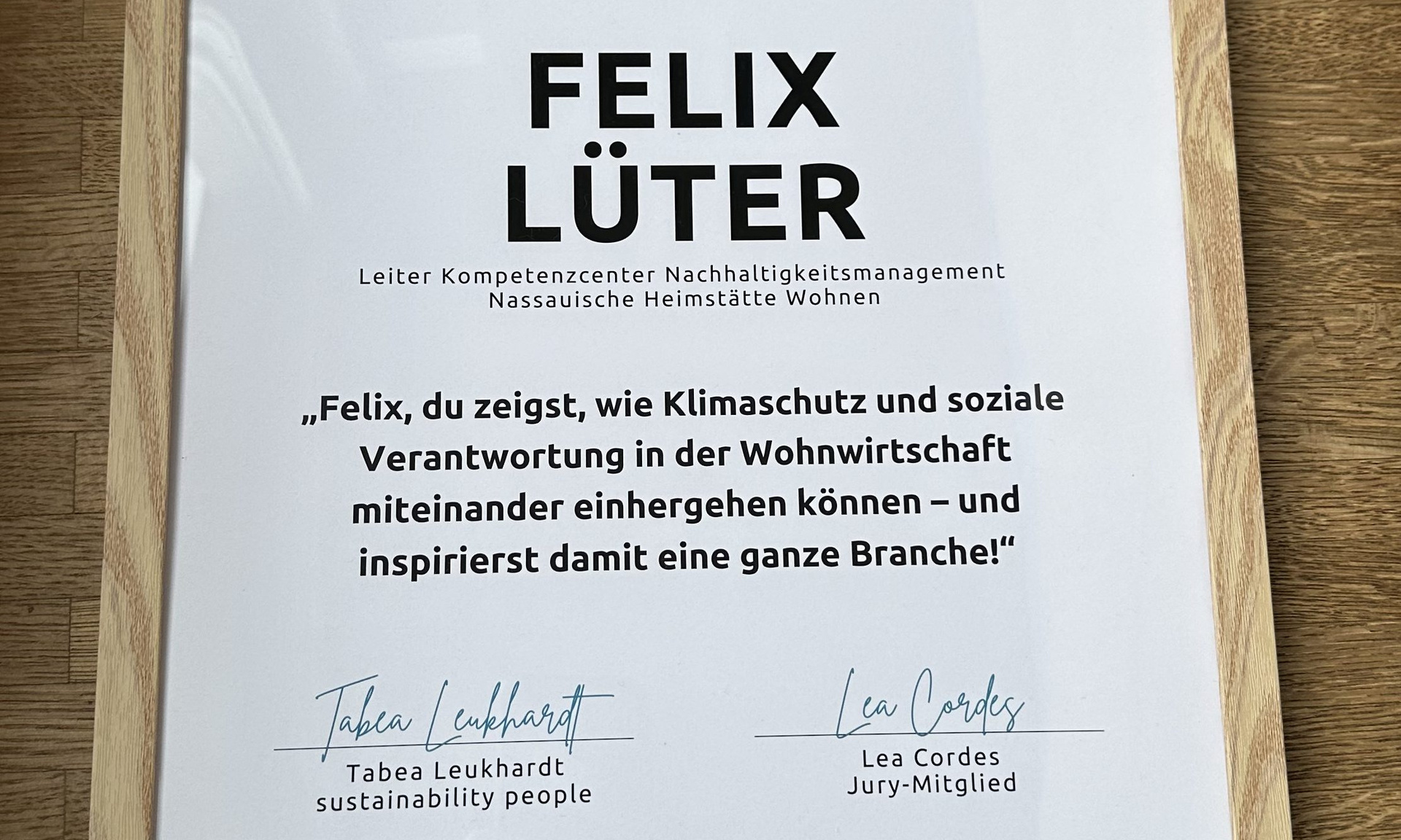 Blick auf die Urkunde von Felix Lüter, Aufschrift: „Felix, du zeigst, wie Klimaschutz und soziale Verantwortung in der Wohnwirtschaft miteinander einhergehen können – und inspirierst damit eine ganze Branche!“