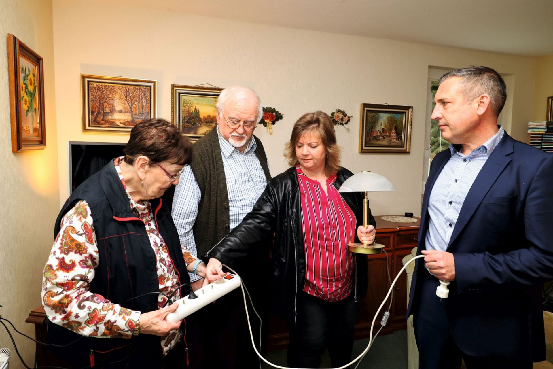Mieter-Ehepaar Scheffer (links) erhält beim Stromspar-Check eine Mehrfachsteckdose mit Schalter von Projektleiterin Silvia Klaffer (2.v.r.) und Sascha Holstein (rechts), Leiter des Regionalcenters Kassel.