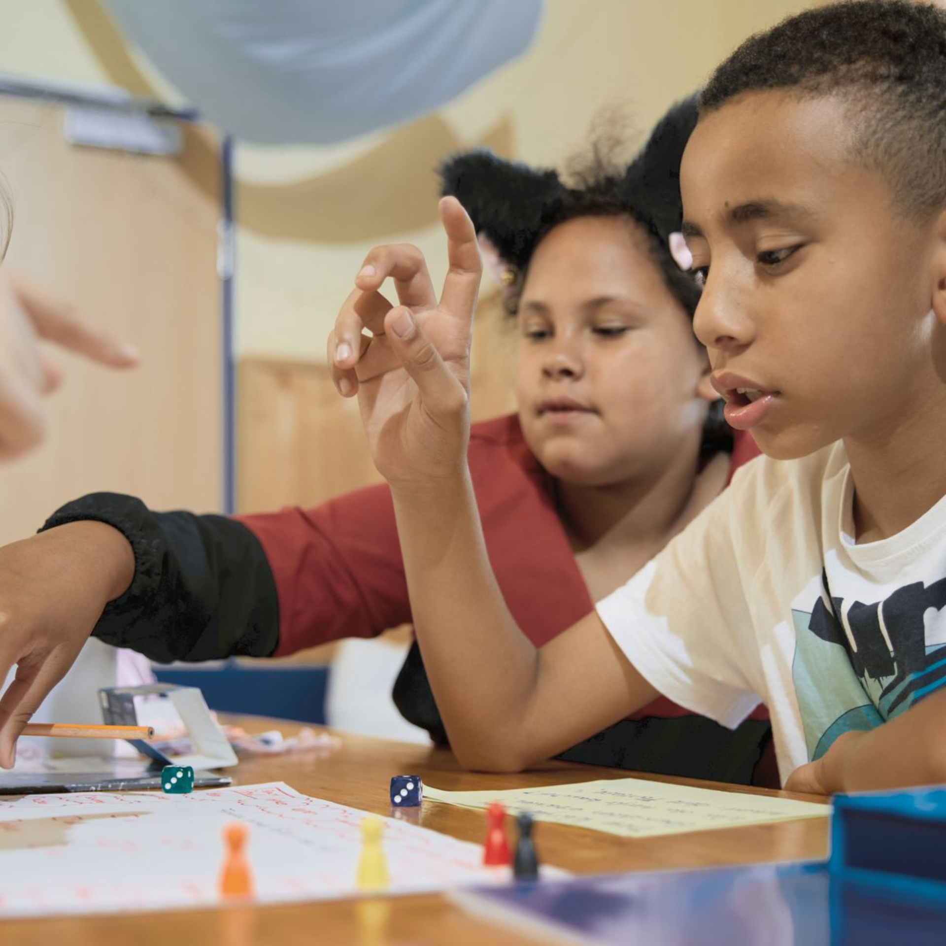 Drei Kinder an einem Tisch die zusammen etwas spielen