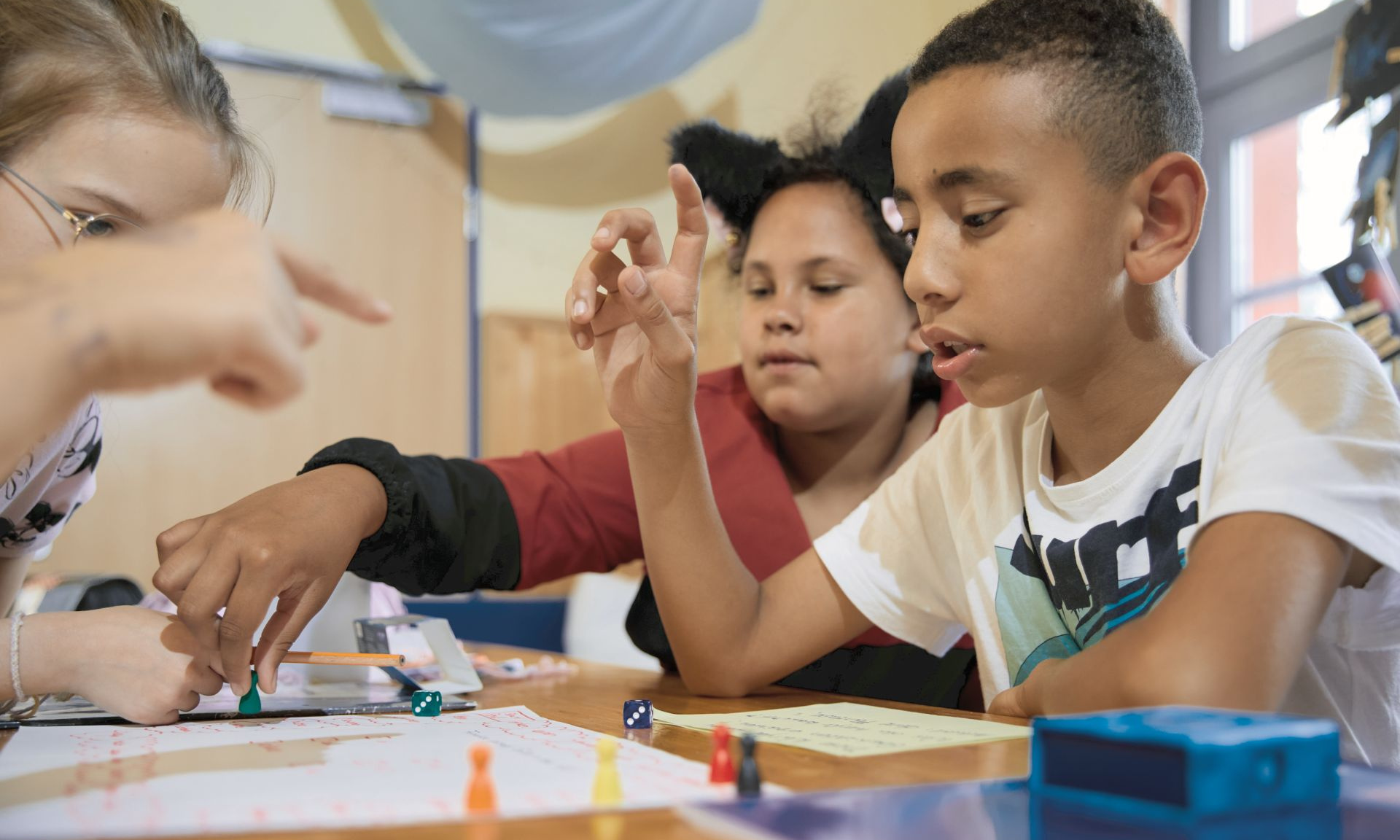 Drei Kinder an einem Tisch die zusammen etwas spielen