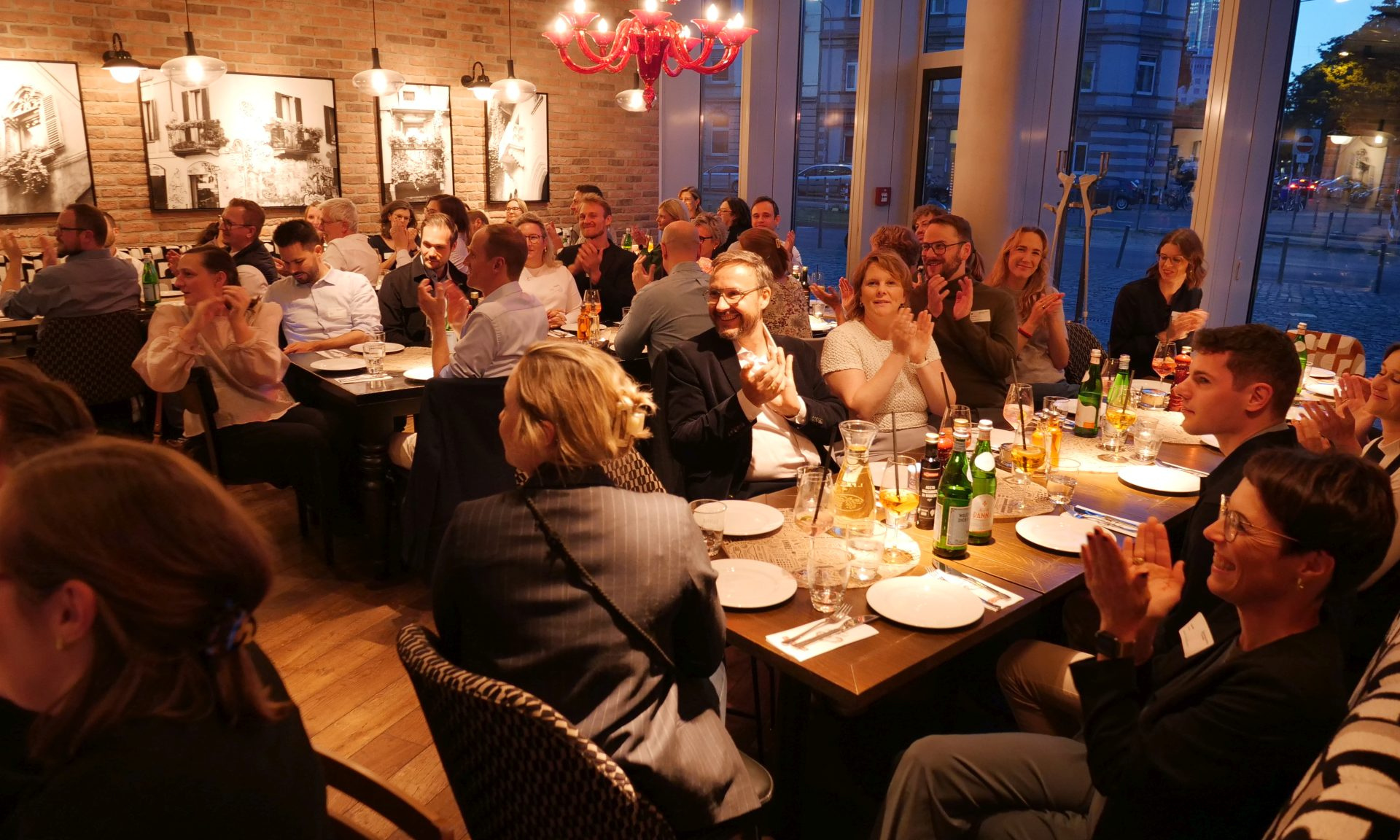 Mehrere Menschen an mehreren Tischen in einem Restaurant. Sie klatschen. Einer von ihnen ist Felix Lüter, Leiter KC Nachhaltigkeitsmanagement bei der NHW