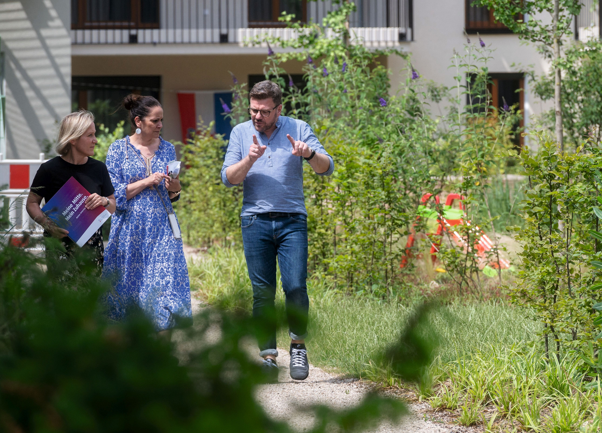 Drei Menschen in Grünanlage vor Haus