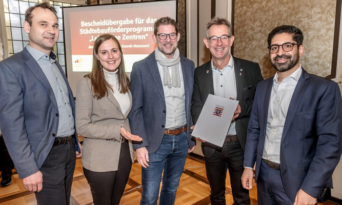 Gruppenfoto: Staatsminister Kaweh Mansoori (re.) hat einen Förderbescheid über 3,3 Millionen Euro an Bürgermeister Christian Schönung (2.v.re.) übergeben. Die ProjektStadt – (v. li.) Christian Schwarzer, Laura Pfisterer und Gregor Voss – unterstützt beim Fördermittelmanagement. 