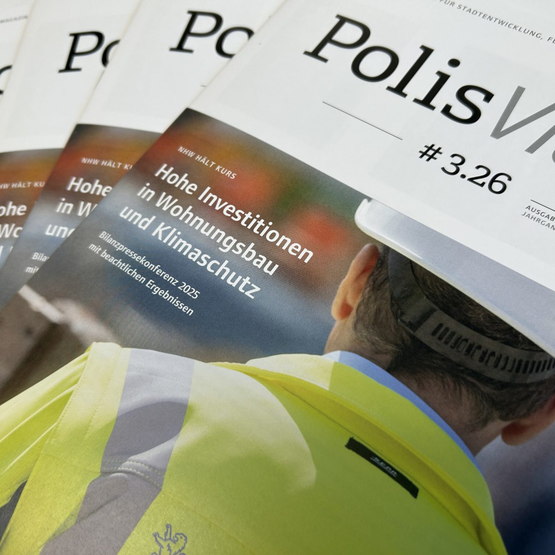 Mehrere aufgefächert fotografierte Ausgaben des NHW-Kundenmagazins PolisVision, Ausgabe 3/26 
