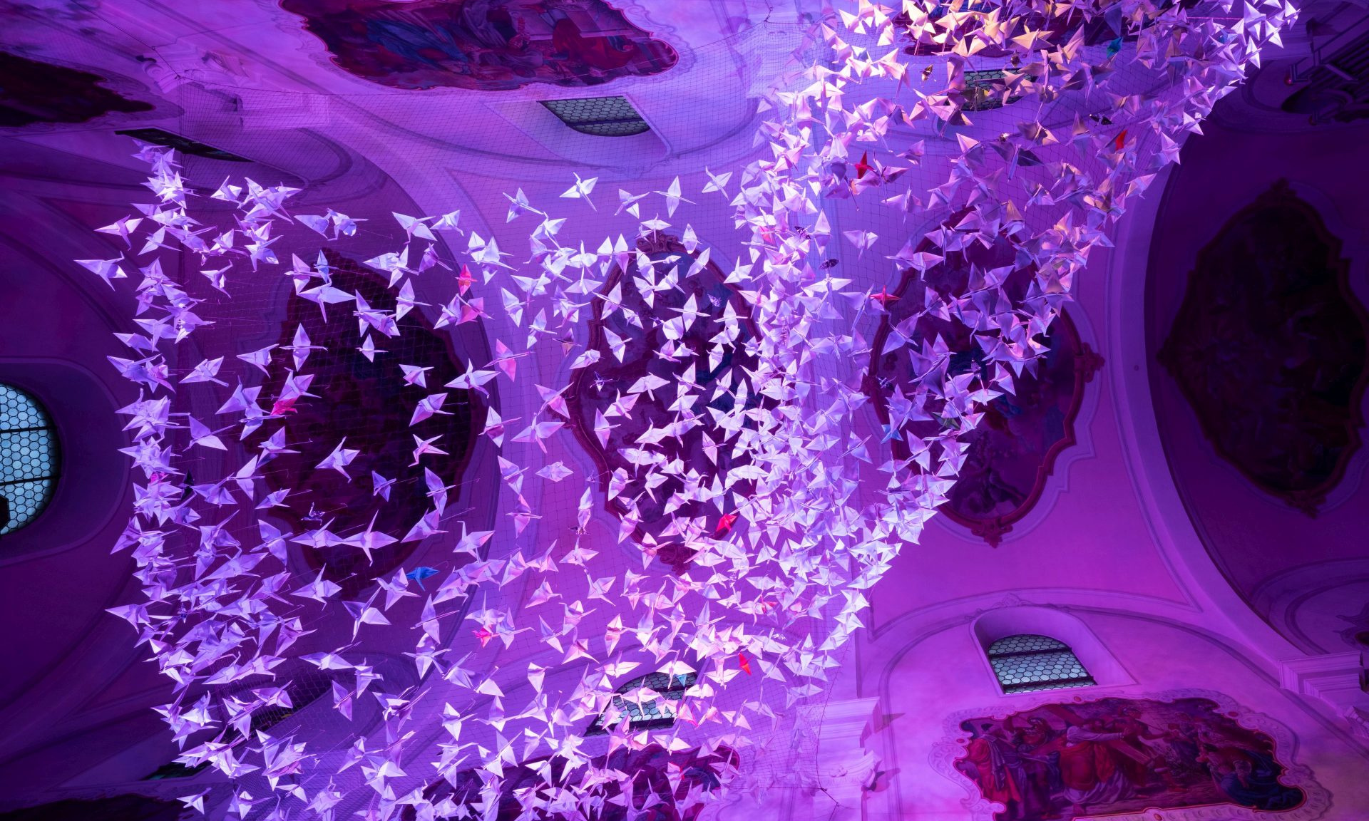 Blick nach oben in der Kelsterbacher Herz-Jesu-Kirche auf 843 Origami-Kraniche - hier lila illuminiert.