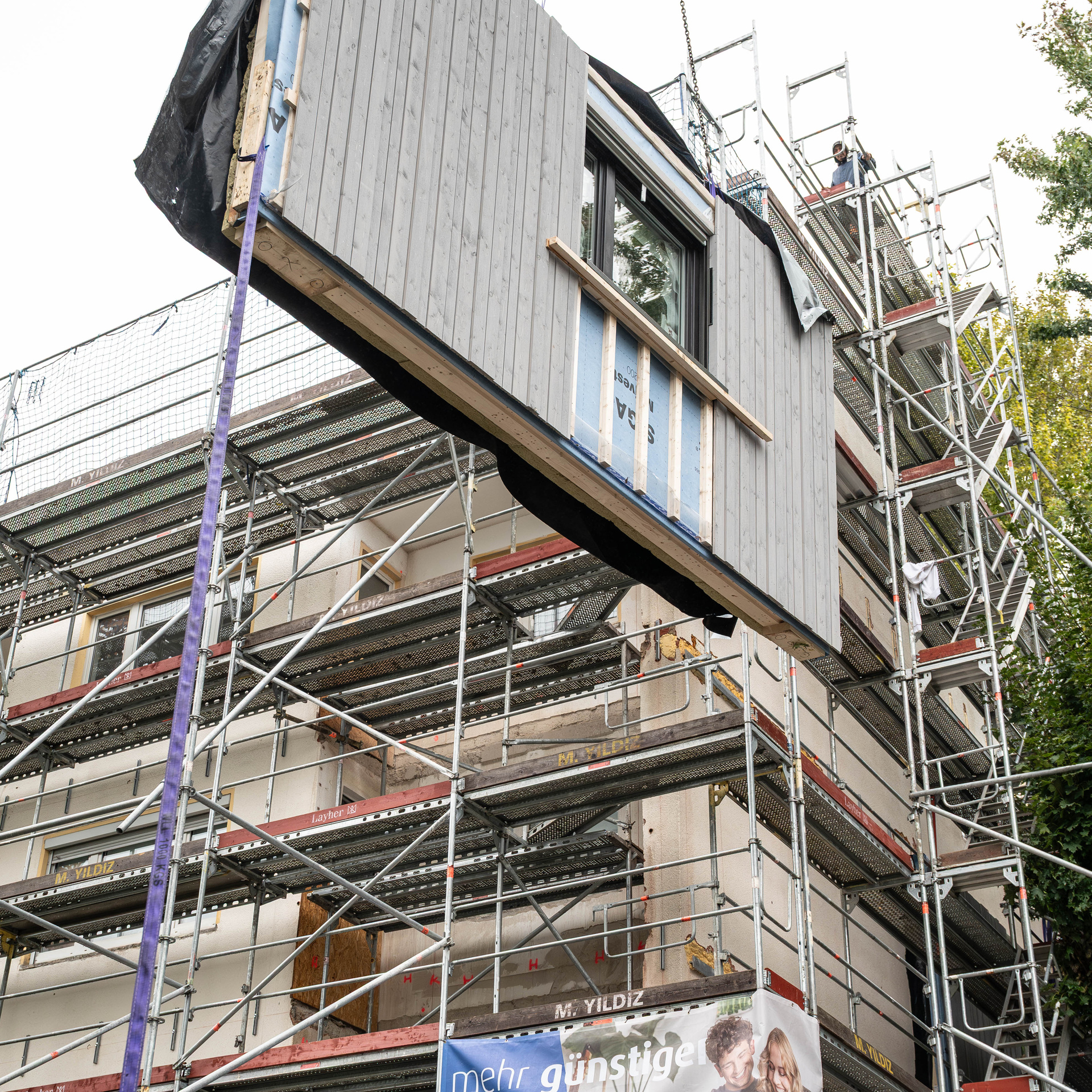 Ein Modul wird an die Fassade gehoben und eingepasst. 
