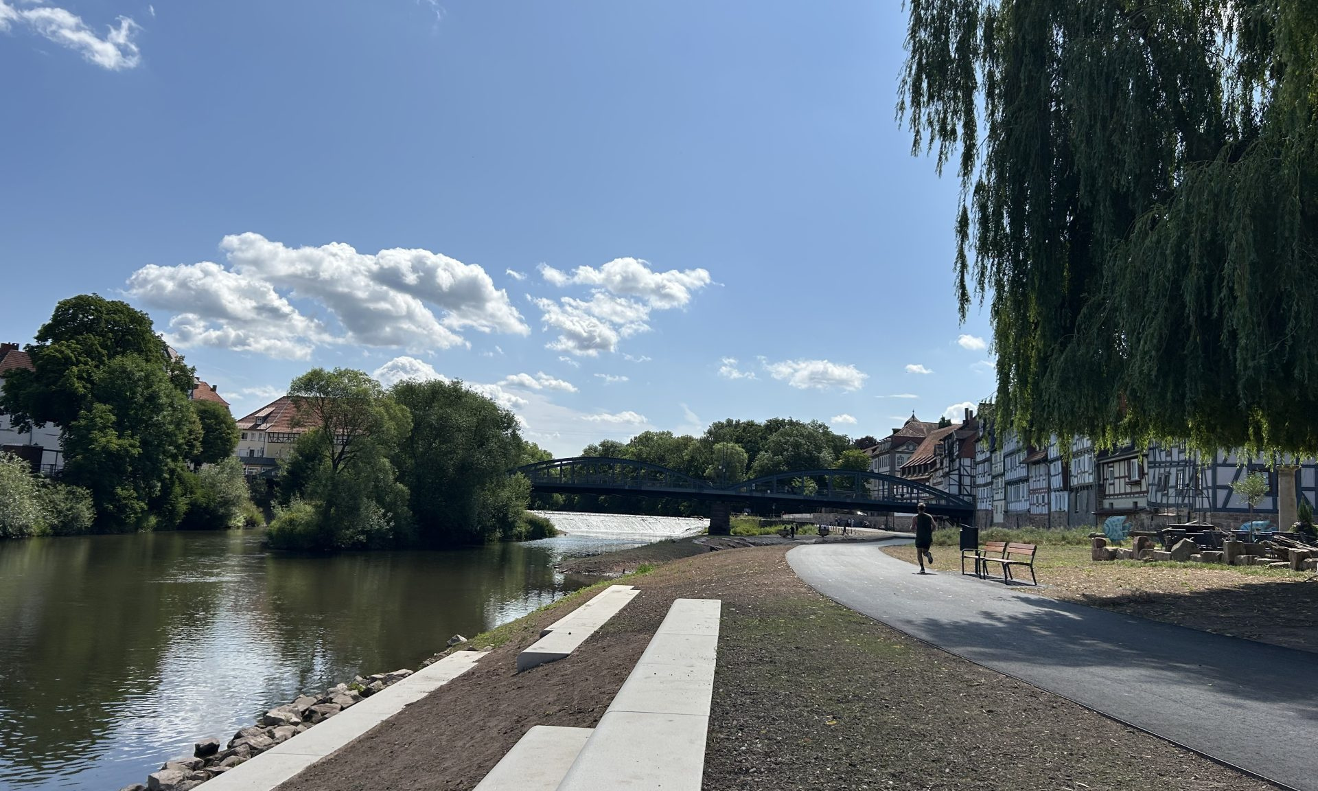 Sitzstufen, ein Weg, Fachwerkhäuser und im Hintergrund eine Brücke