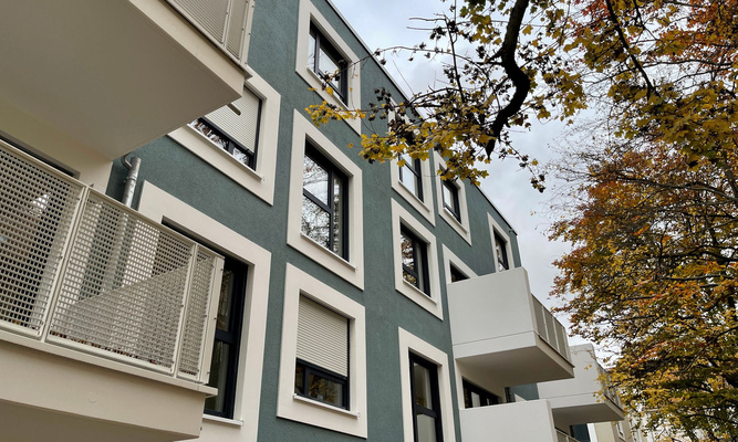 Mehrfamilienhaus mit Baum und Balkonen